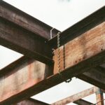 Close-up of rusty steel beams and chains in outdoor industrial construction site.